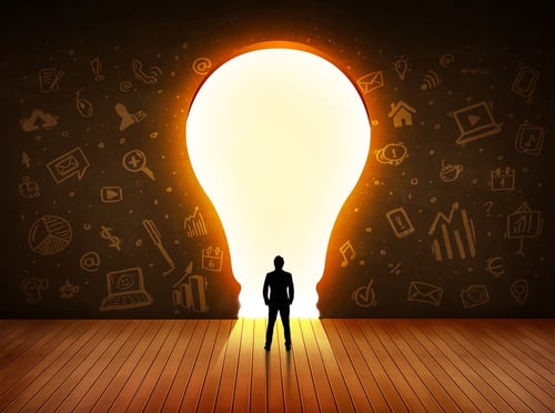 Business man looking at bright light bulb in the wall concept.jpeg