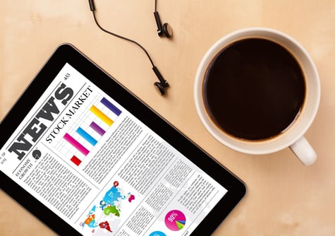 Workplace with tablet pc showing latest news and a cup of coffee on a wooden work table close-up.jpeg